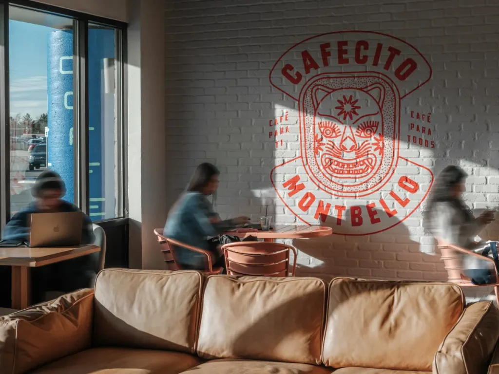 People sitting and working inside Cafecito coffee shop with mural wall and seating area