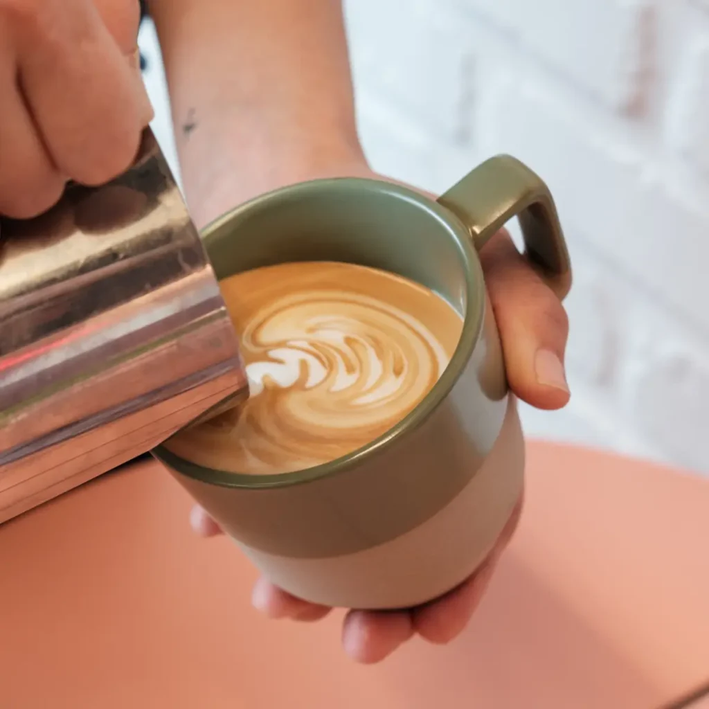 Café con leche with latte art being poured